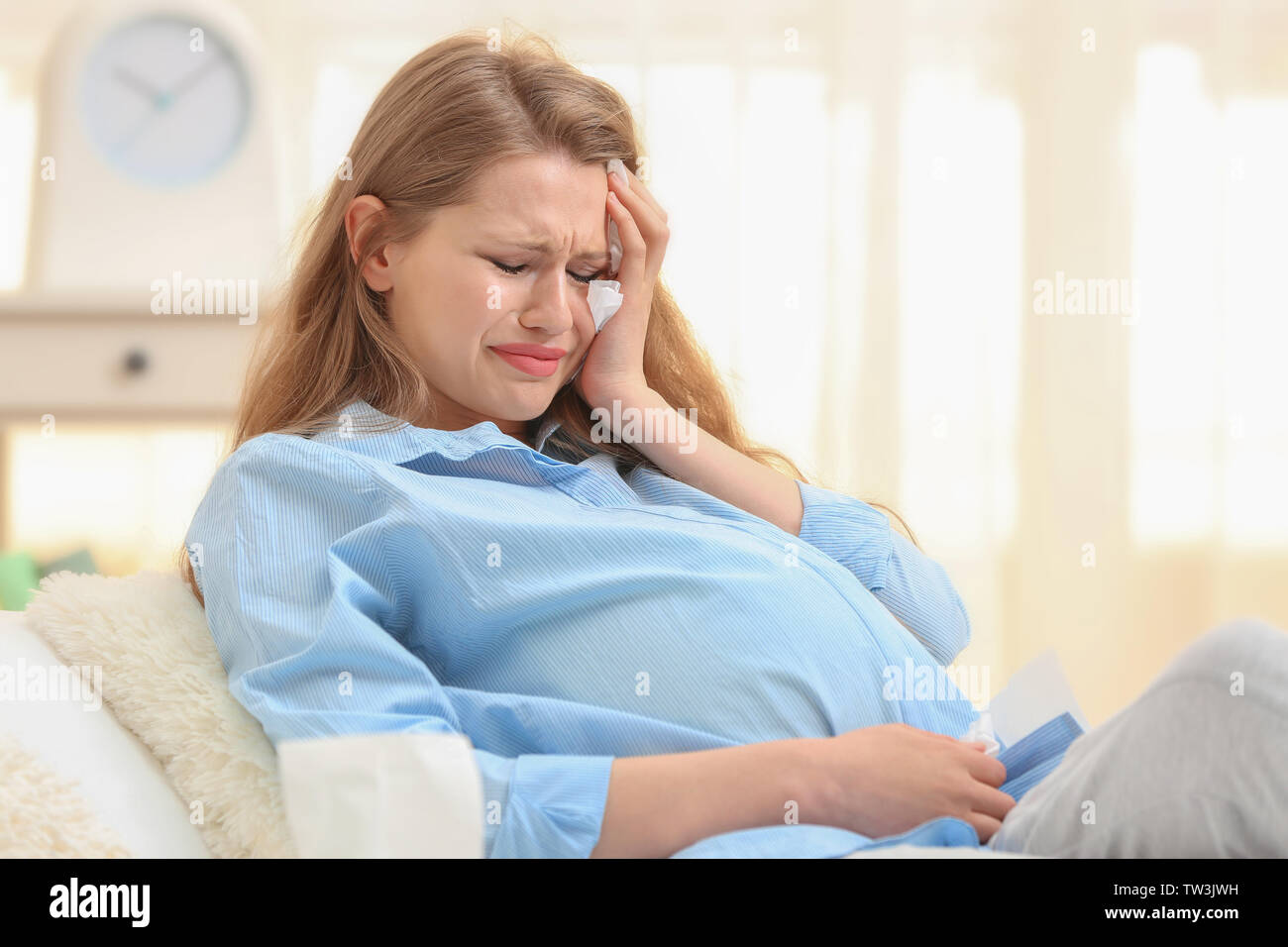 Beautiful pregnant woman crying in light room. Pregnancy hormones concept Stock Photo