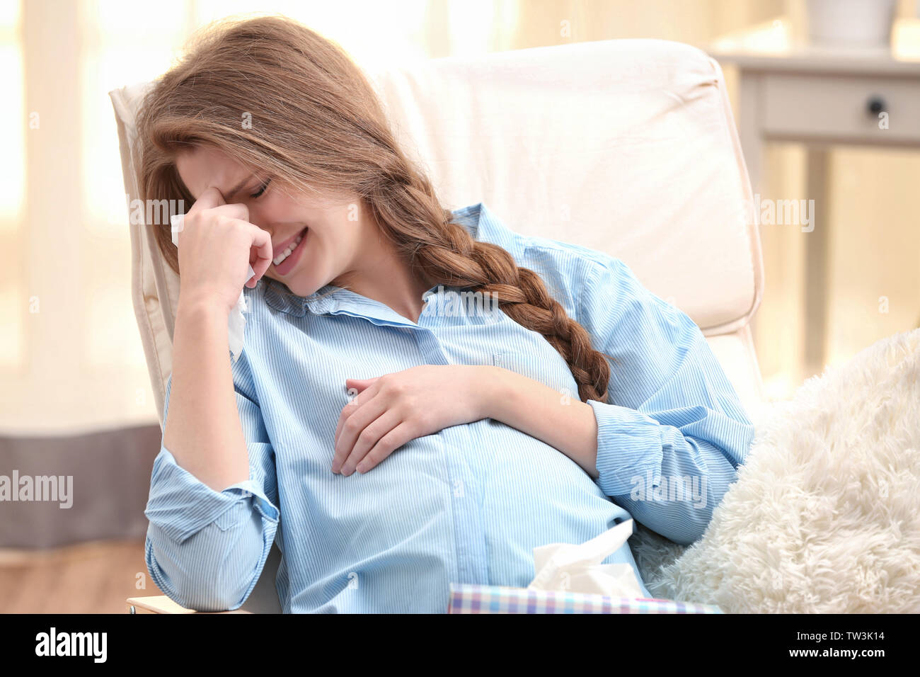 Emotional pregnant woman sitting in arm chair and crying. Pregnancy
