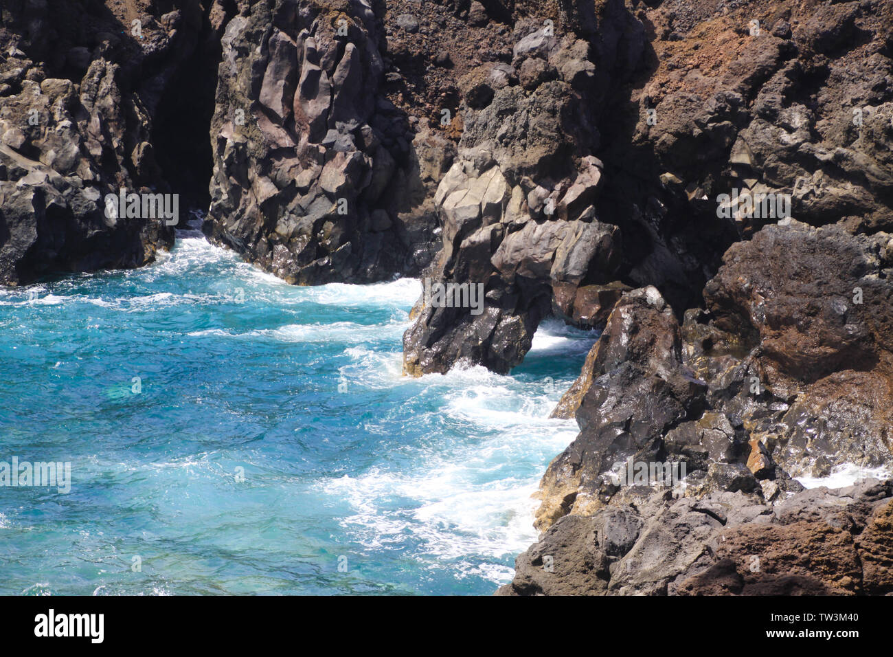 View on rugged rough coastline with sharp cliffs. lagoon with turquoise blue water, waves - Los Hervidereos, Lanzarote Stock Photo