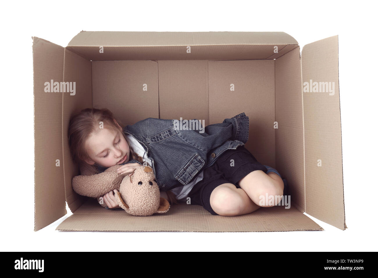 Poor little girl sleeping in cardboard box on white background Stock Photo