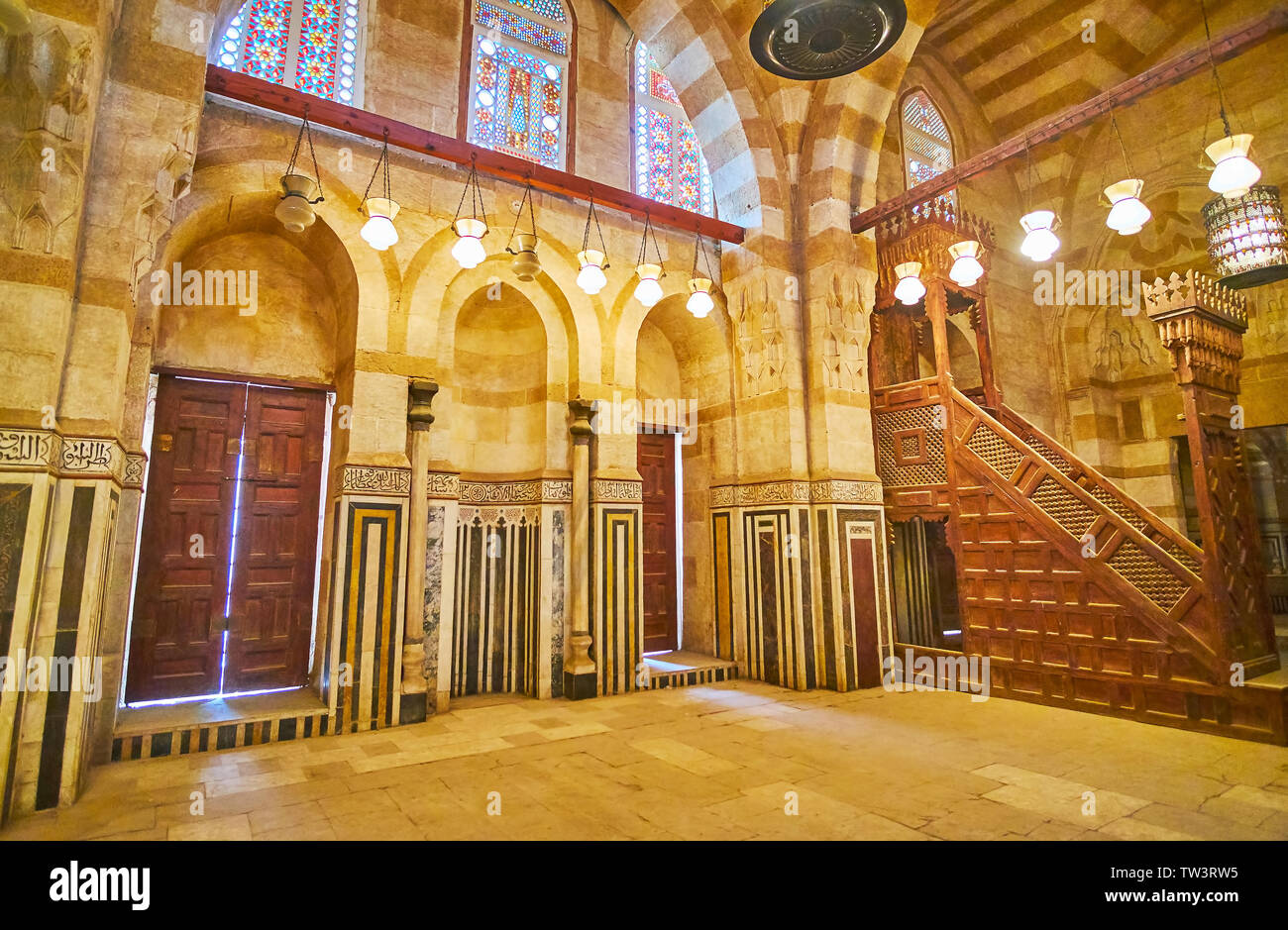 CAIRO, EGYPT - DECEMBER 22, 2017: The scenic interior of medieval Khayrbak Mosque with stone inlay, stained glass windows, vintage lamps and carved wo Stock Photo