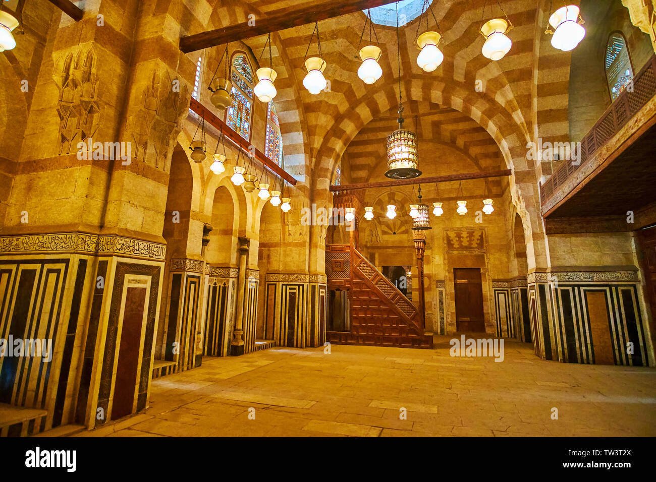 CAIRO, EGYPT - DECEMBER 22, 2017: The prayer hall of the Khayrbak mosque with rich stone decorations, wooden minbar and vintage lamps, on December 22 Stock Photo