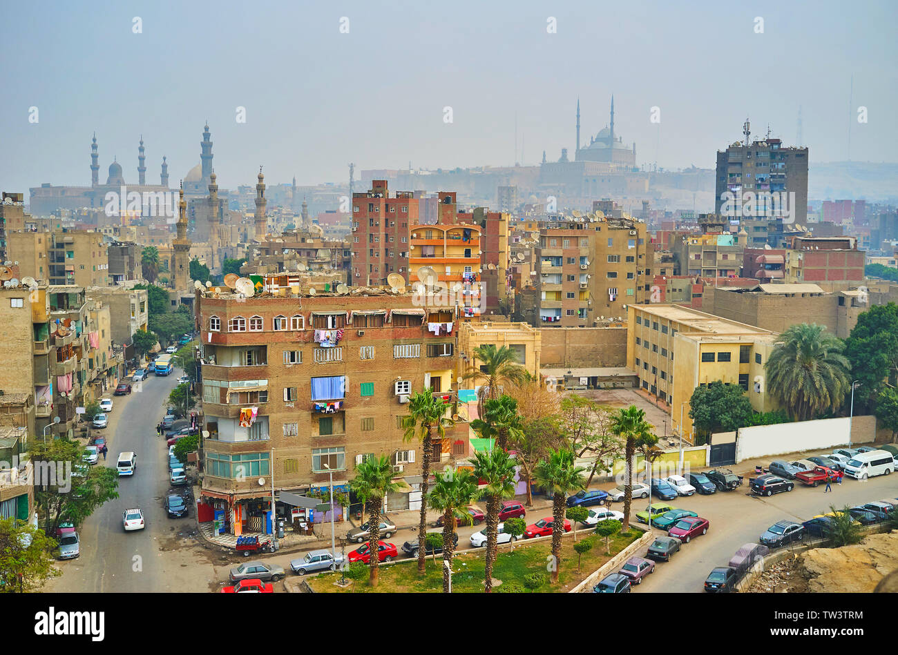 The minarets of Al-Rifai, Sultan Hassan mosques and the Alabaster mosque of Cairo Citadel are seen behind the dusty high-rises of Al Sayeda Zeinab dis Stock Photo