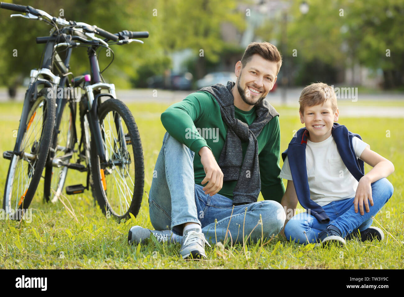 Dad and son sitting on grass in green park Stock Photo - Alamy