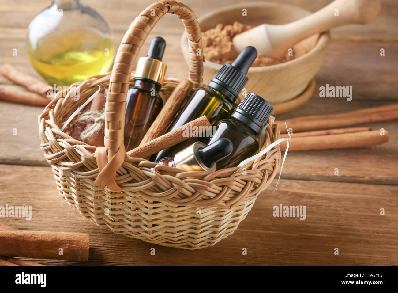 Bottles of cinnamon oil in basket on wooden background Stock Photo
