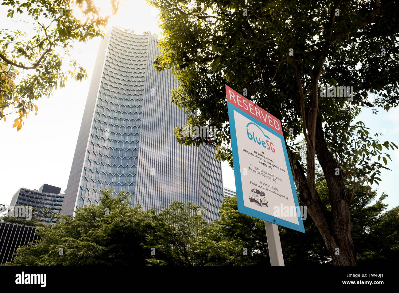 A sign showing reserved spot for Blue SG car sharing electric car space in Singapore with skyscraper in the background. Stock Photo