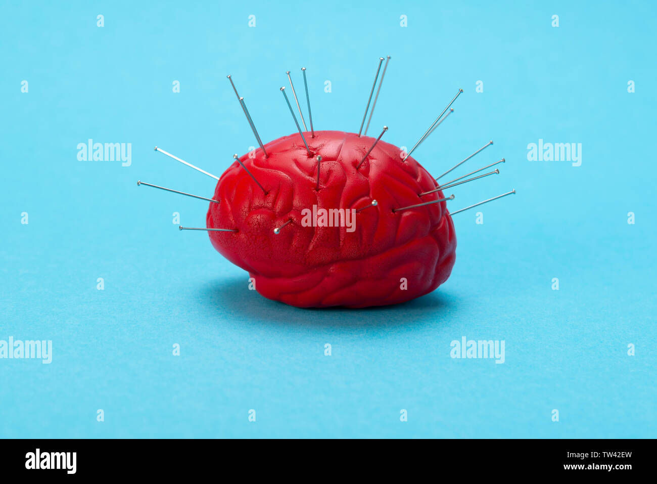 Red brain on a blue background with injected needles. Brain control concept. Brain treatment. Stock Photo