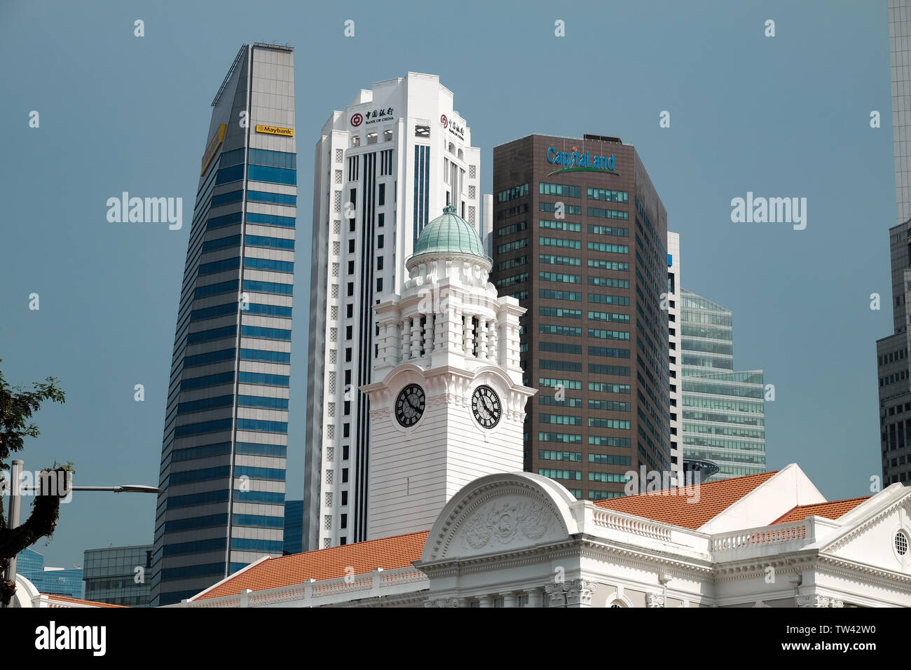 A cityscape view of the clock tower of Victoria Theatre and Concert hall with the skyscrapers of Singapore financial district behind Stock Photo