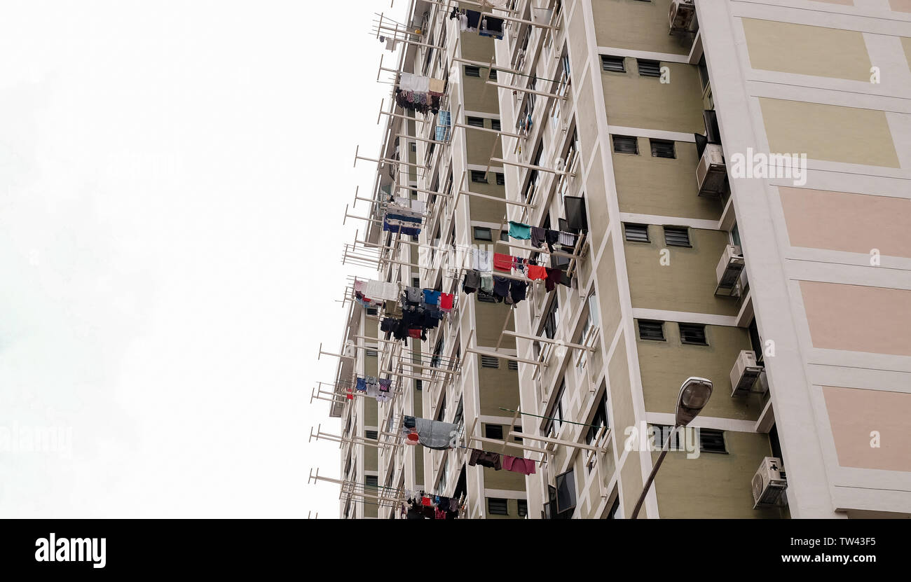 Residential high-rise accommodation with laundry clothes washing hung outside on rails out of the windows in Singapore. Stock Photo