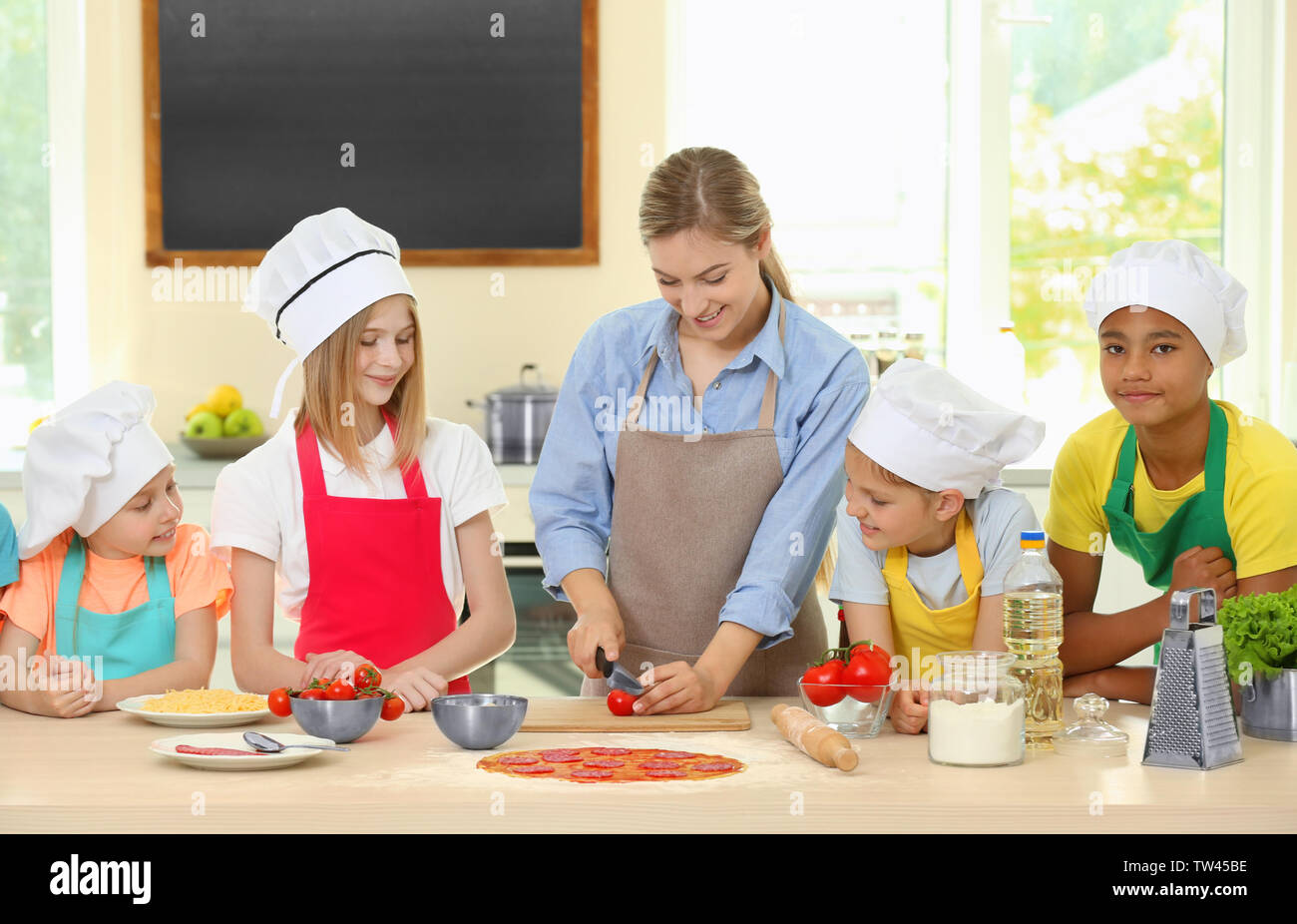 Group of children and teacher in kitchen during cooking classes Stock