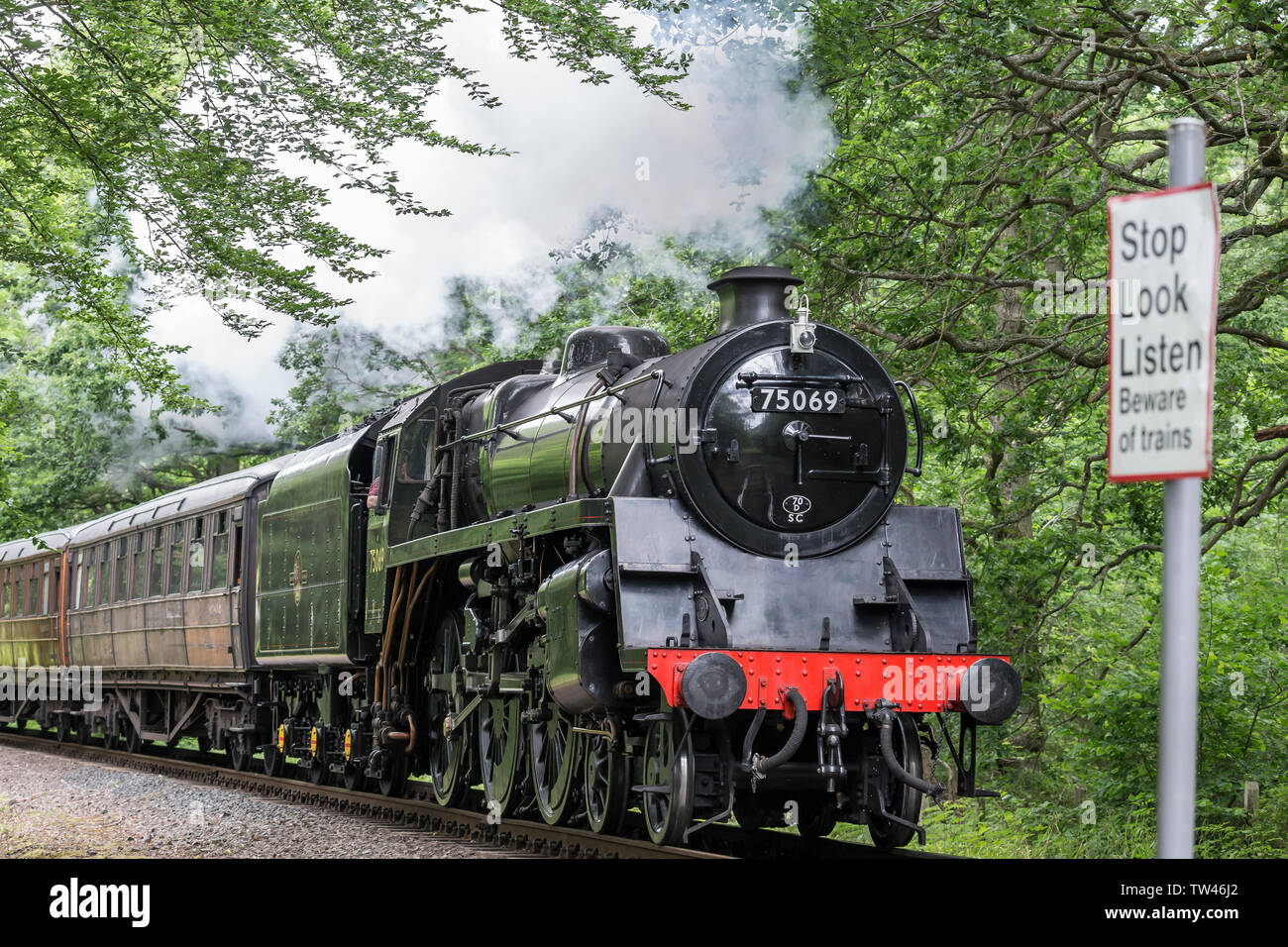 Close up of isolated vintage UK steam train front approaching, passing through rural summer countryside on heritage railway line. Vintage locomotive. Stock Photo