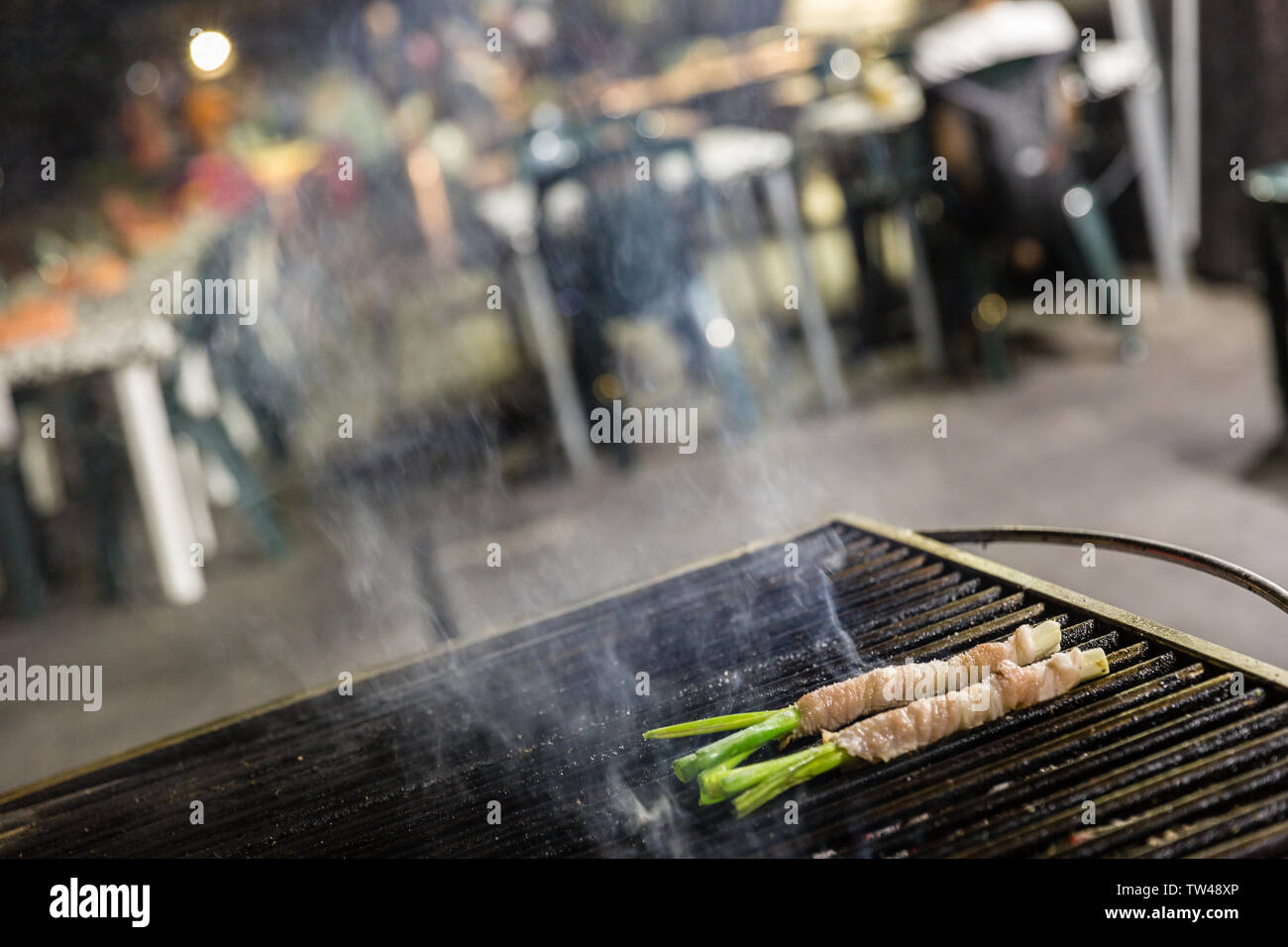 Mangia e bevi, typical Palermo street food. Bacon and chives on a grill Stock Photo