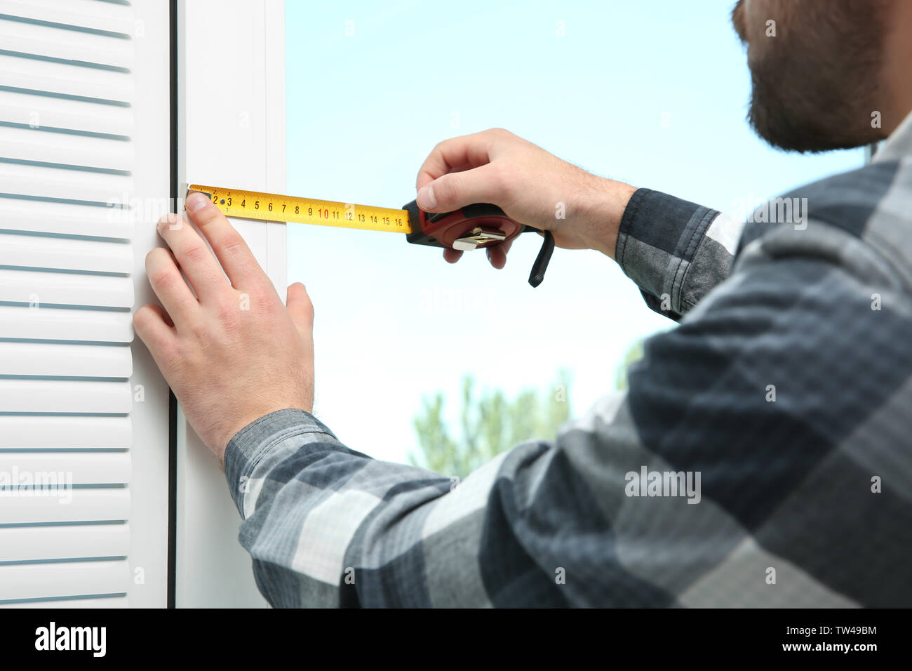 Young man installing window shades at home Stock Photo