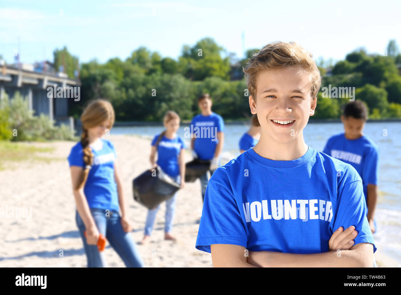 Young boy standing with crossed hands outdoors. Volunteer concept ...