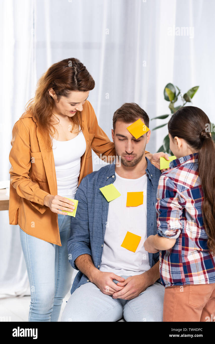 Upset Notes happy woman and kid putting yellow sticky notes on upset man Stock ...