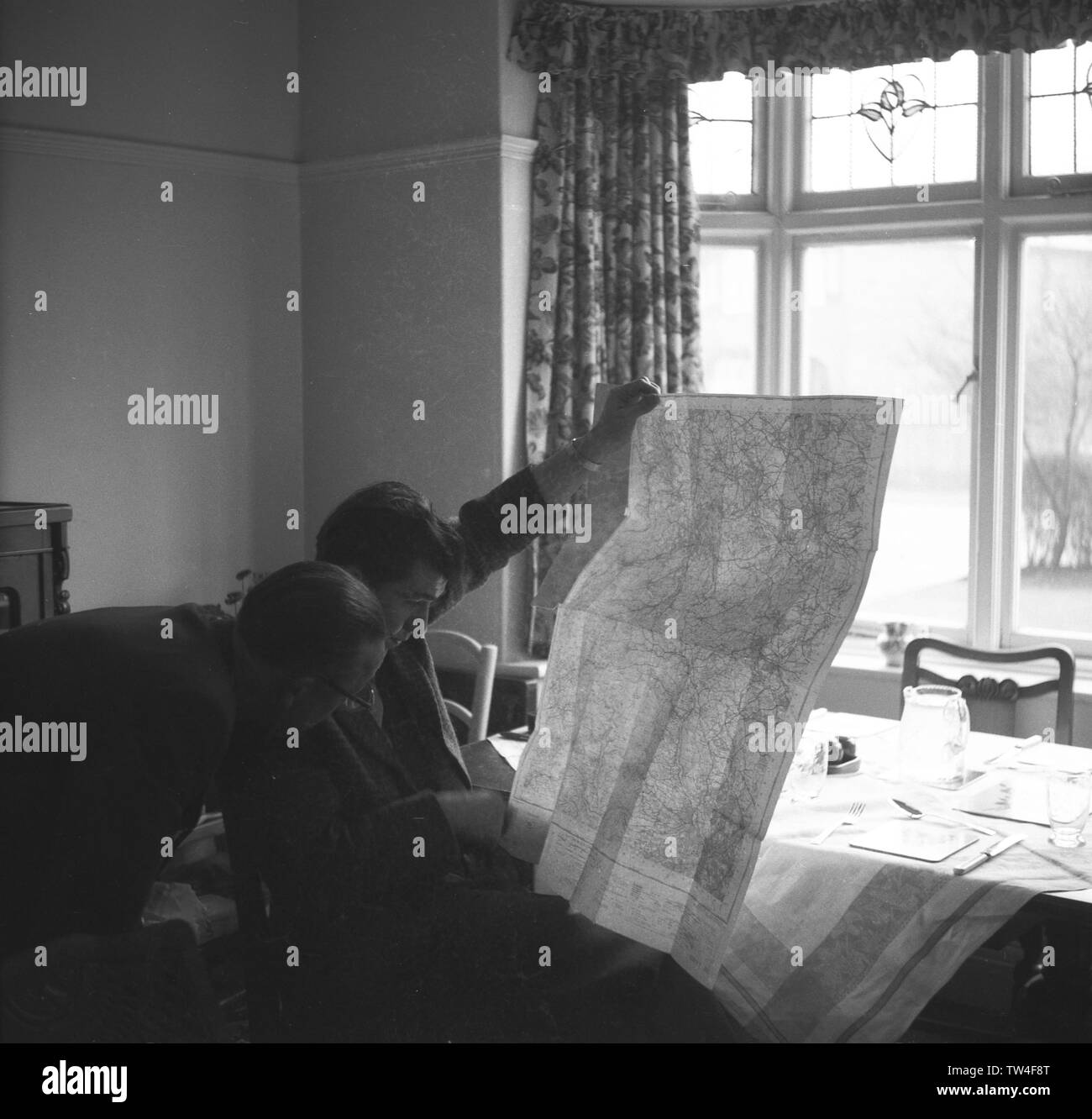 1950s, historical, people in a front room looking at  a map, England, UK. Stock Photo