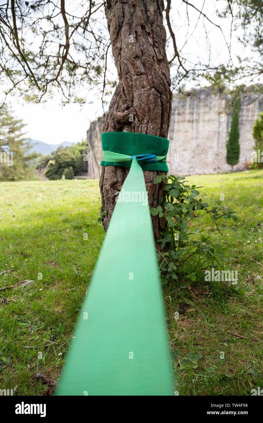 Slackline sport tape attached to the trunk of a tree ready to be used. Stock Photo