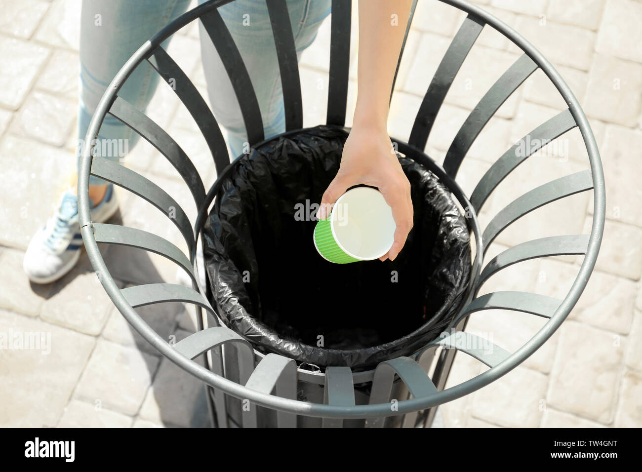 Young woman throwing paper cup in litter bin outdoors Stock Photo - Alamy