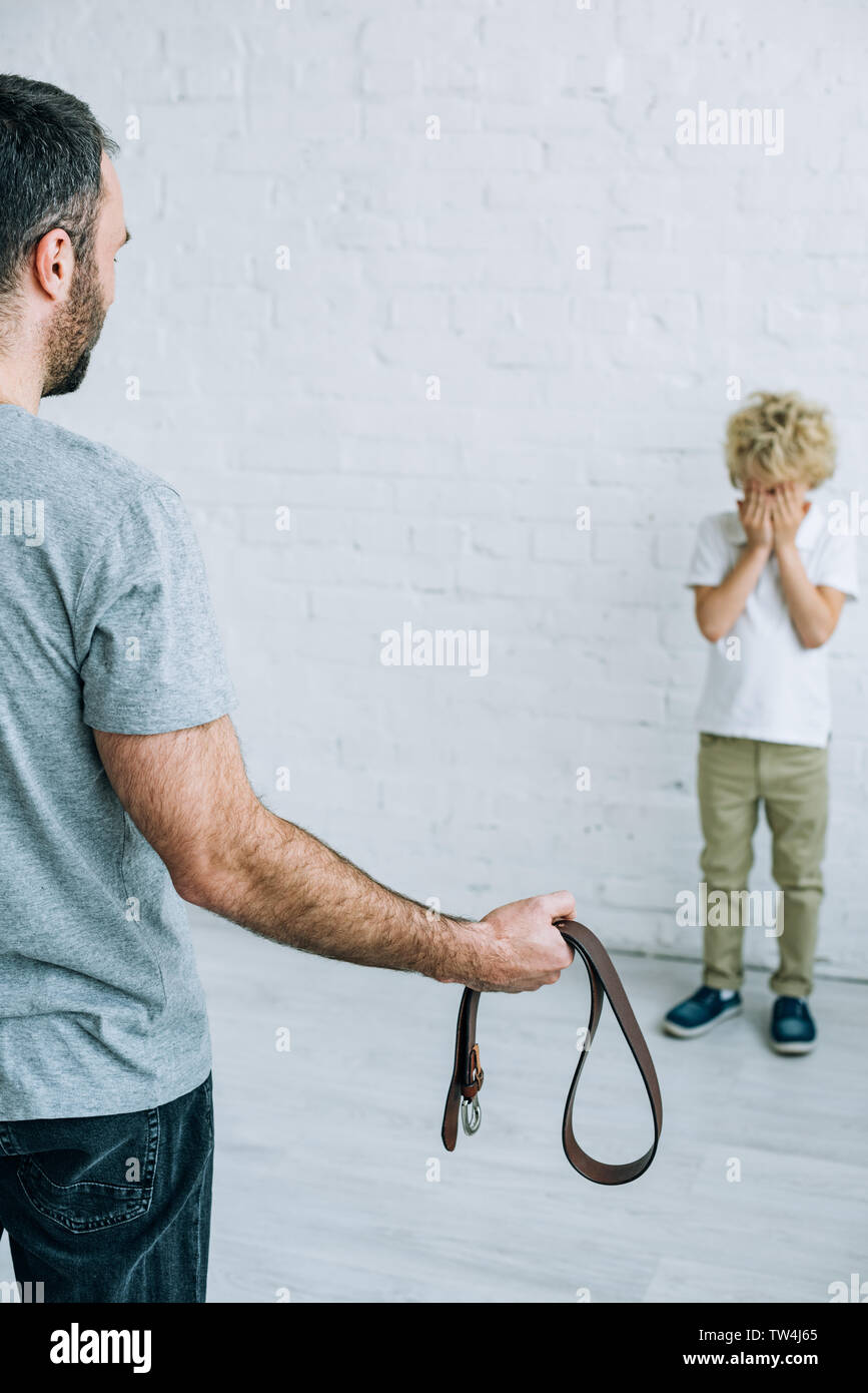 cropped view of father with belt and crying son at home Stock Photo Alamy