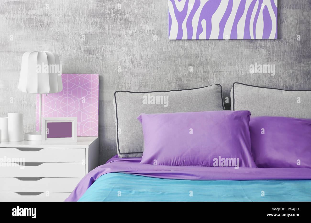 Lilac accent in modern interior. Comfortable bed with pillows in room Stock Photo Alamy