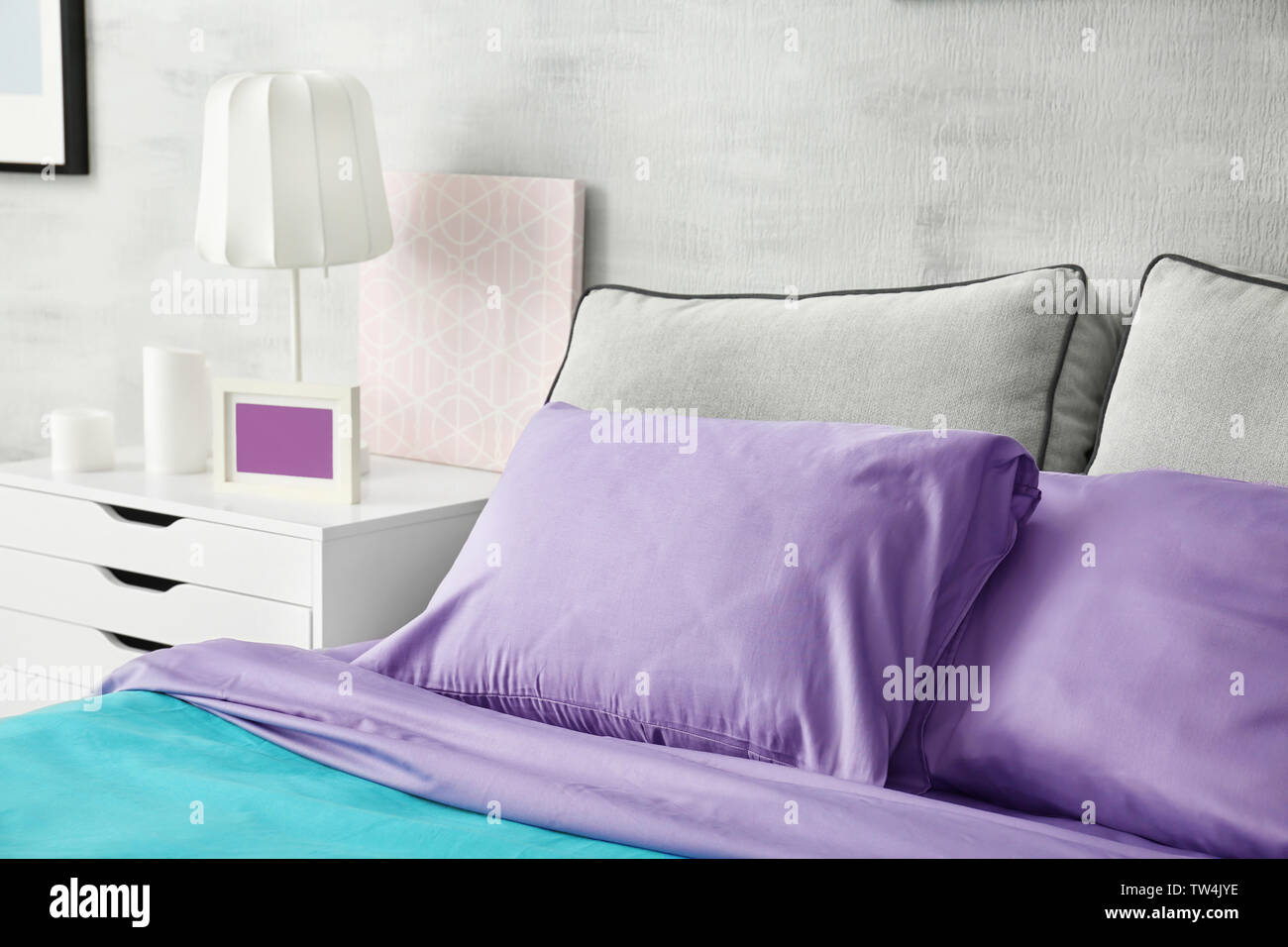 Lilac accent in modern interior. Comfortable bed with pillows in room Stock Photo Alamy