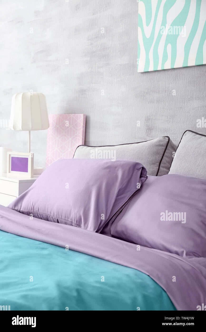 Lilac accent in modern interior. Comfortable bed with pillows in room Stock Photo Alamy