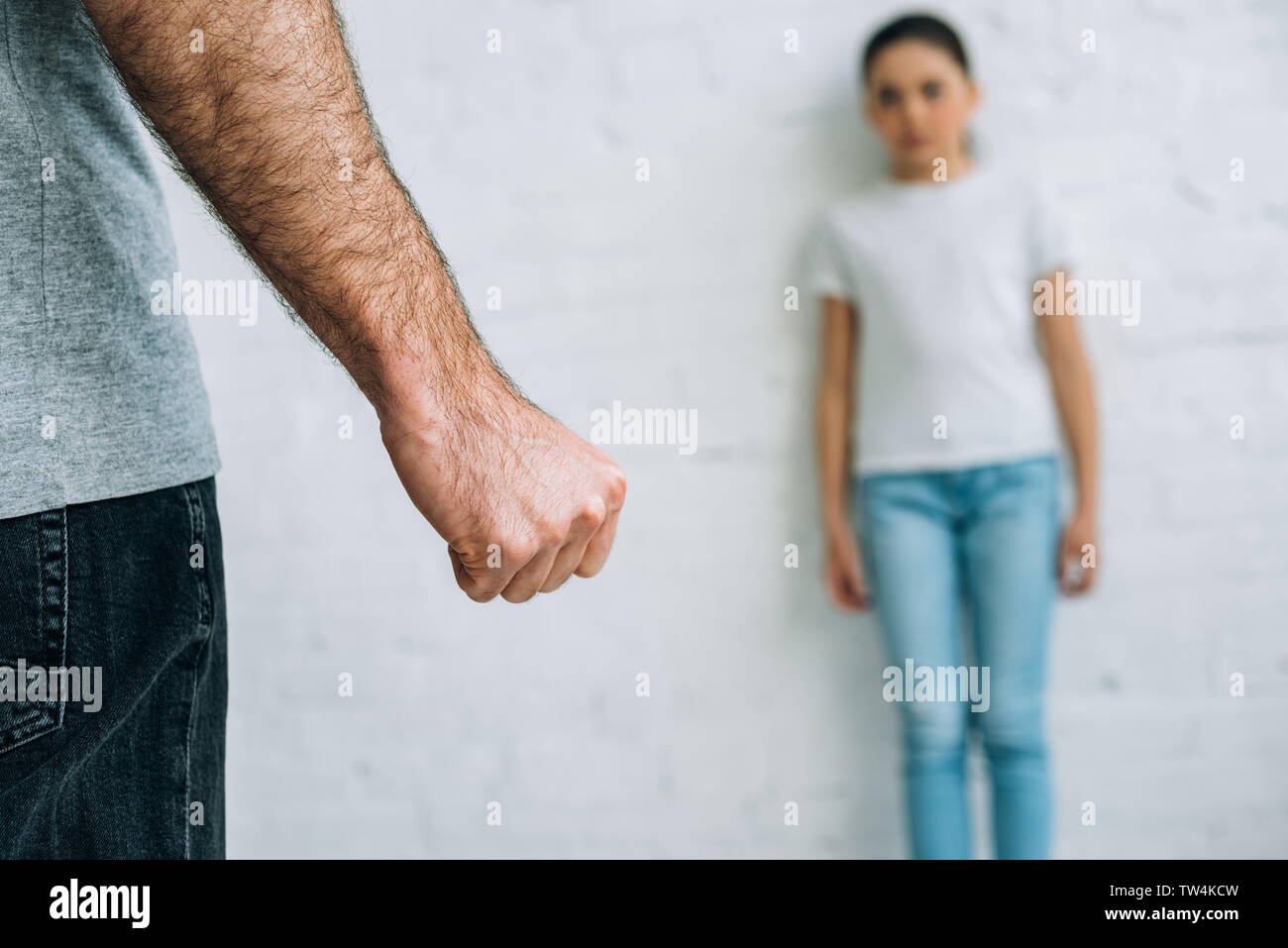partial view of abusive father and scared daughter at home Stock Photo
