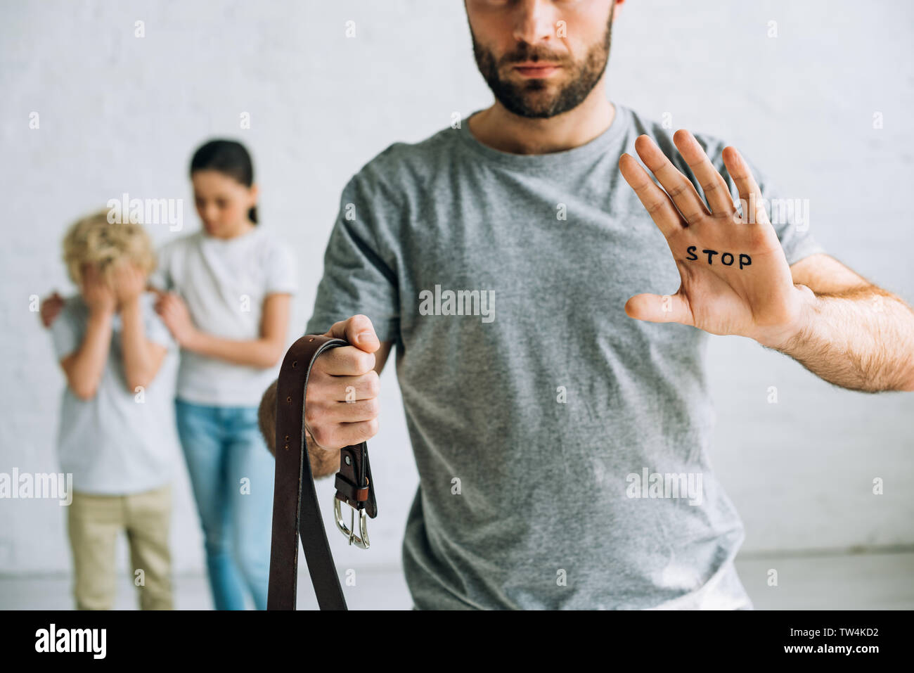 partial view of abusive father with inscription on palm and sad kids Stock Photo