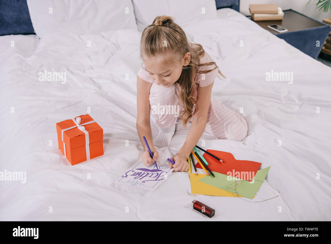 adorable child drawing on fathers day greeting card near gift box and ...