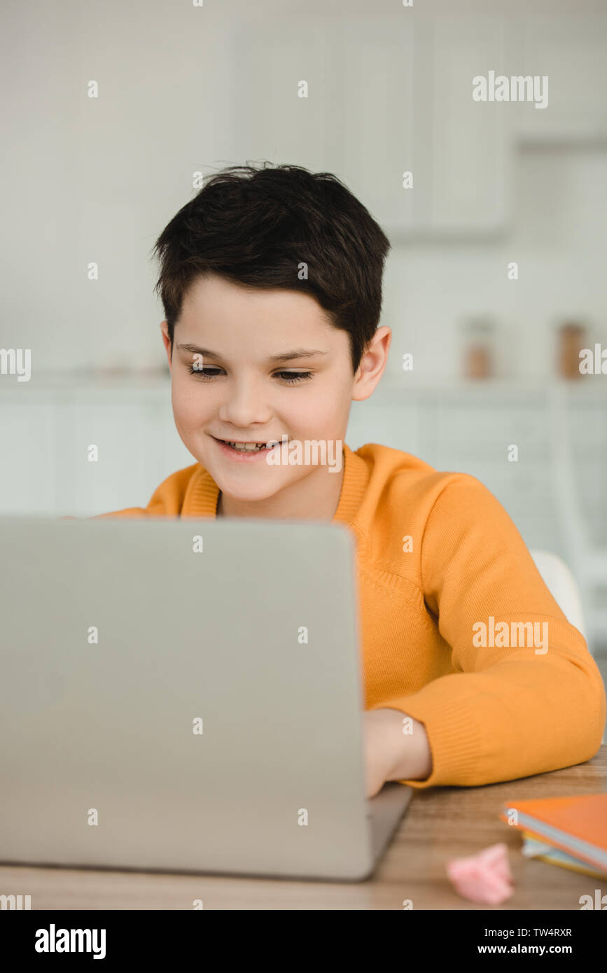 smiling attentive boy using laptop while doing schoolwork at home Stock Photo
