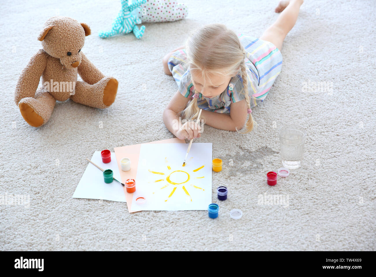 Cute little girl painting picture and spilled water on carpet Stock Photo -  Alamy