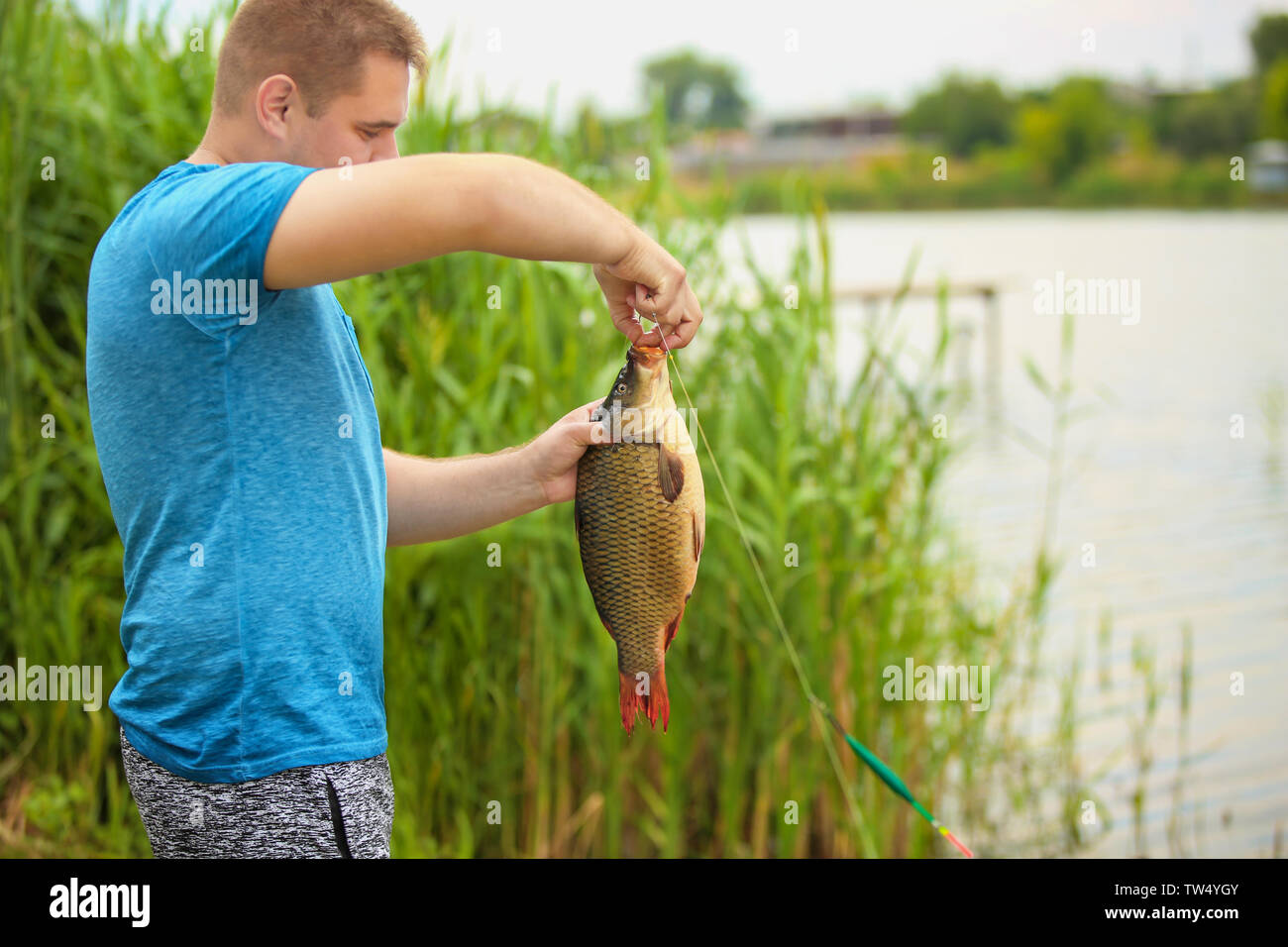 Man Getting Fish Man with freshly caught fish on river bank Stock Photo - Alamy