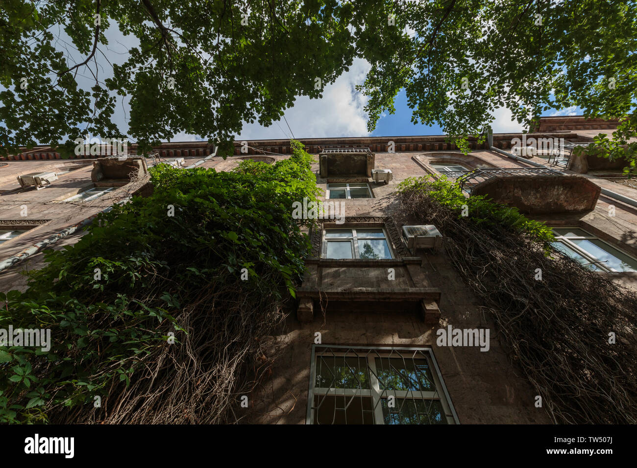 old and residential multi storey house in Armenia with vegetation Stock