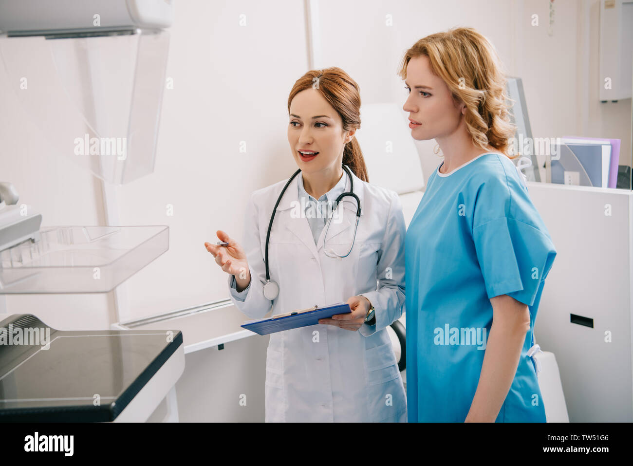 beautiful young radiologist in white coat showing x-ray machine to ...