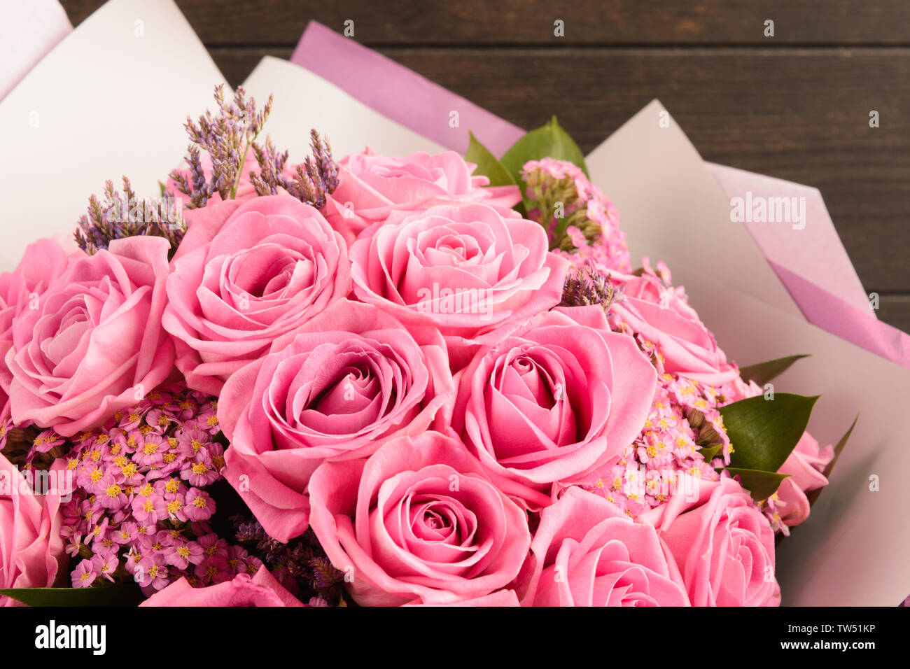 Beautiful bouquet of pink roses for Valentine's day in pink and grey paper with wooden