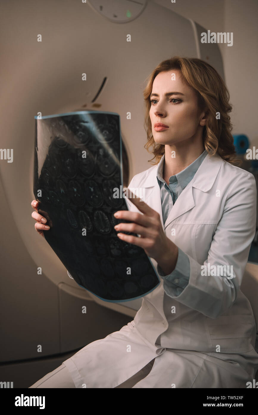 attentive radiologist examining x-ray diagnosis while sitting near computed tomography scanner Stock Photo