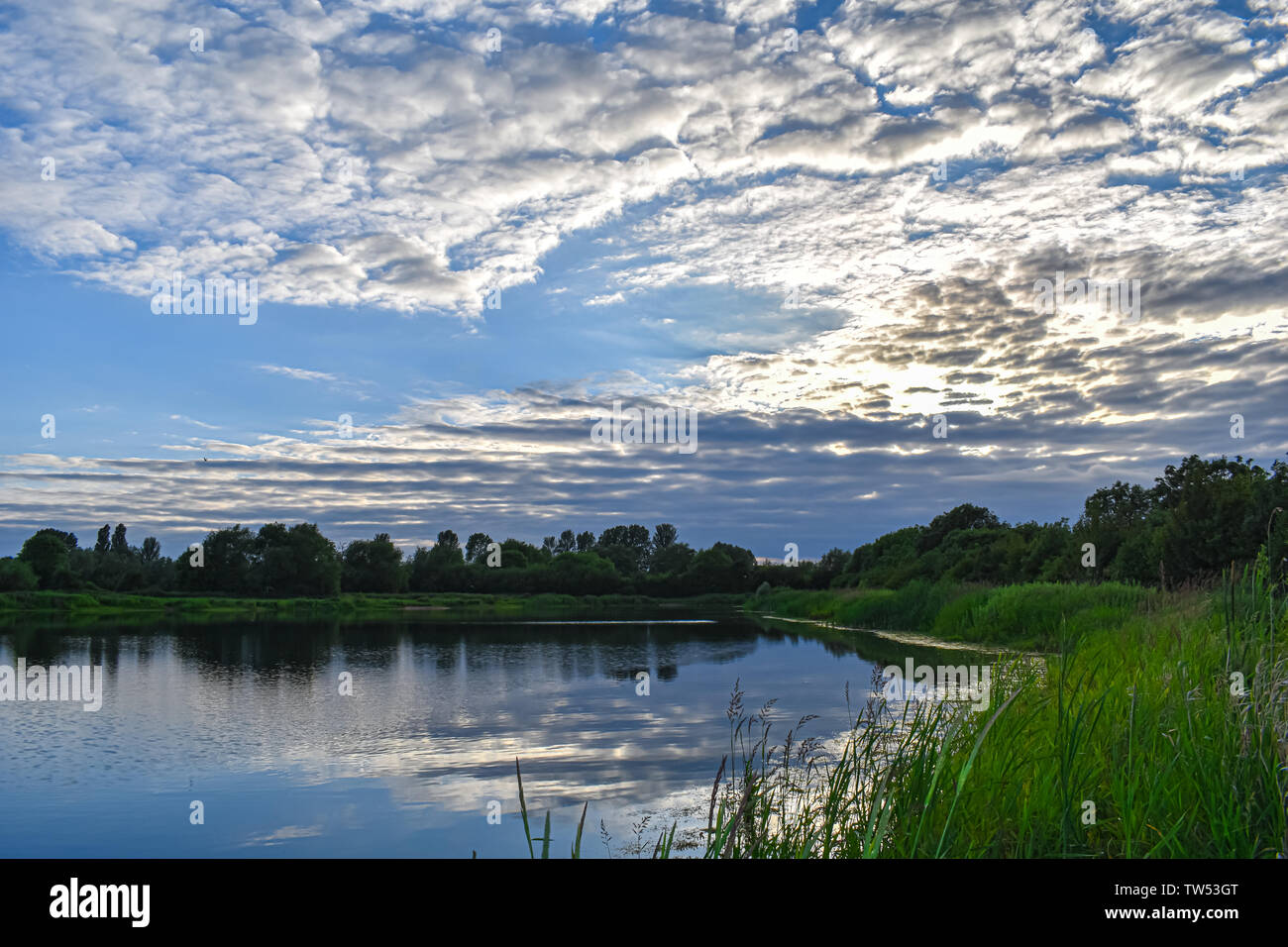 Nature Reserve in Oxfordshire England. Beautiful Lake reflects the blue sky above on a Summer evening. Stock Photo
