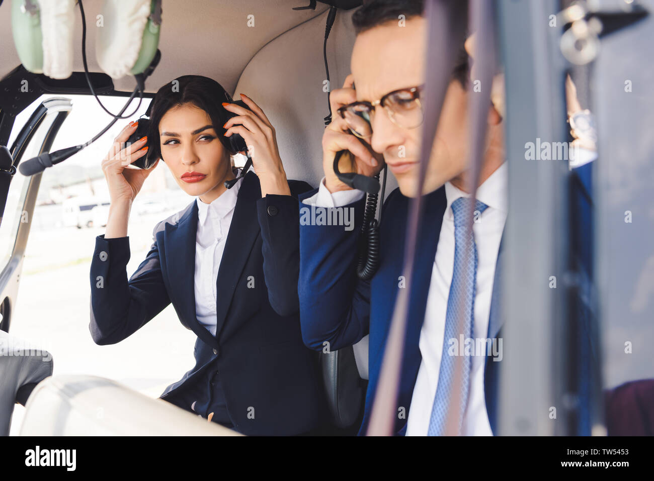 businesswoman and businessman in headsets sitting in helicopter cabin Stock Photo