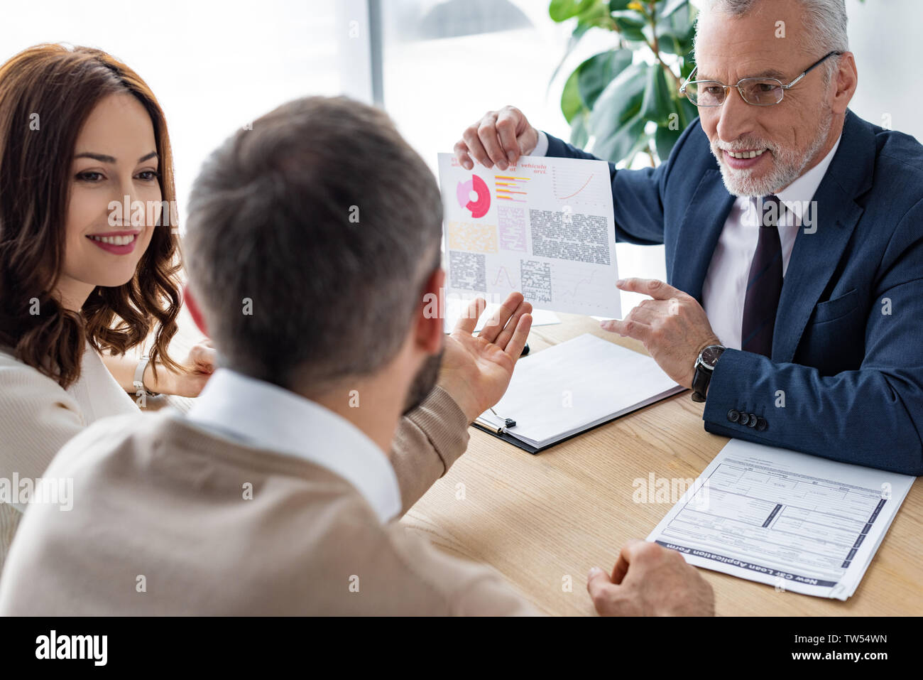 back view of man gesturing near cheerful woman and car dealer with