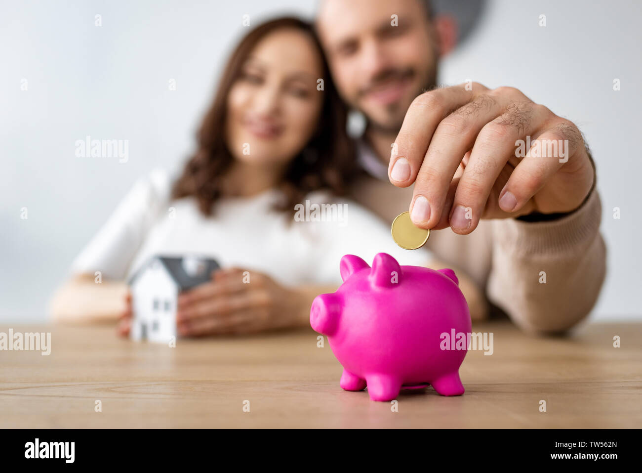 selective focus of man putting coin in pink piggy bank and cheerful ...