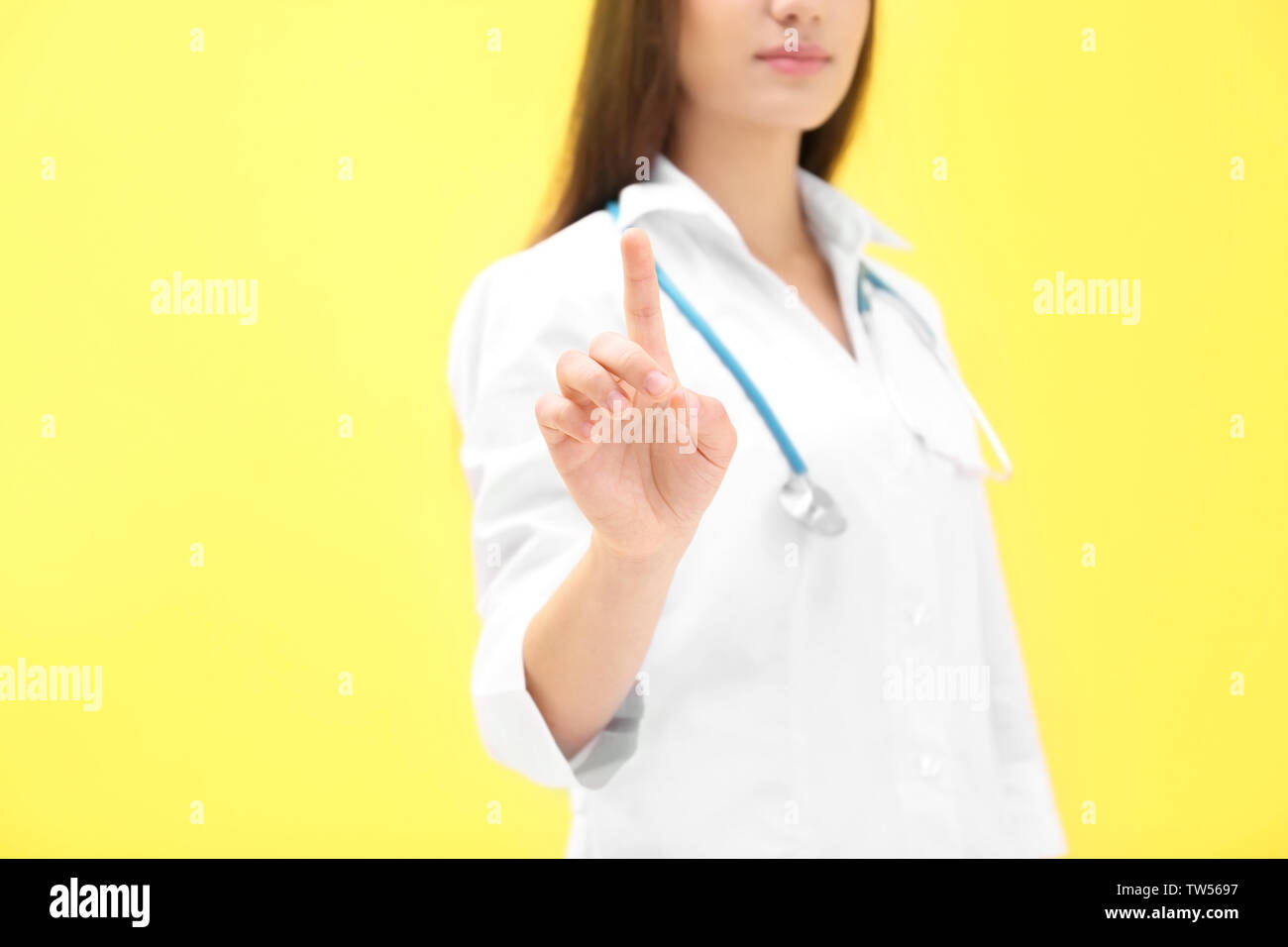 Young doctor using virtual screen, on color background Stock Photo