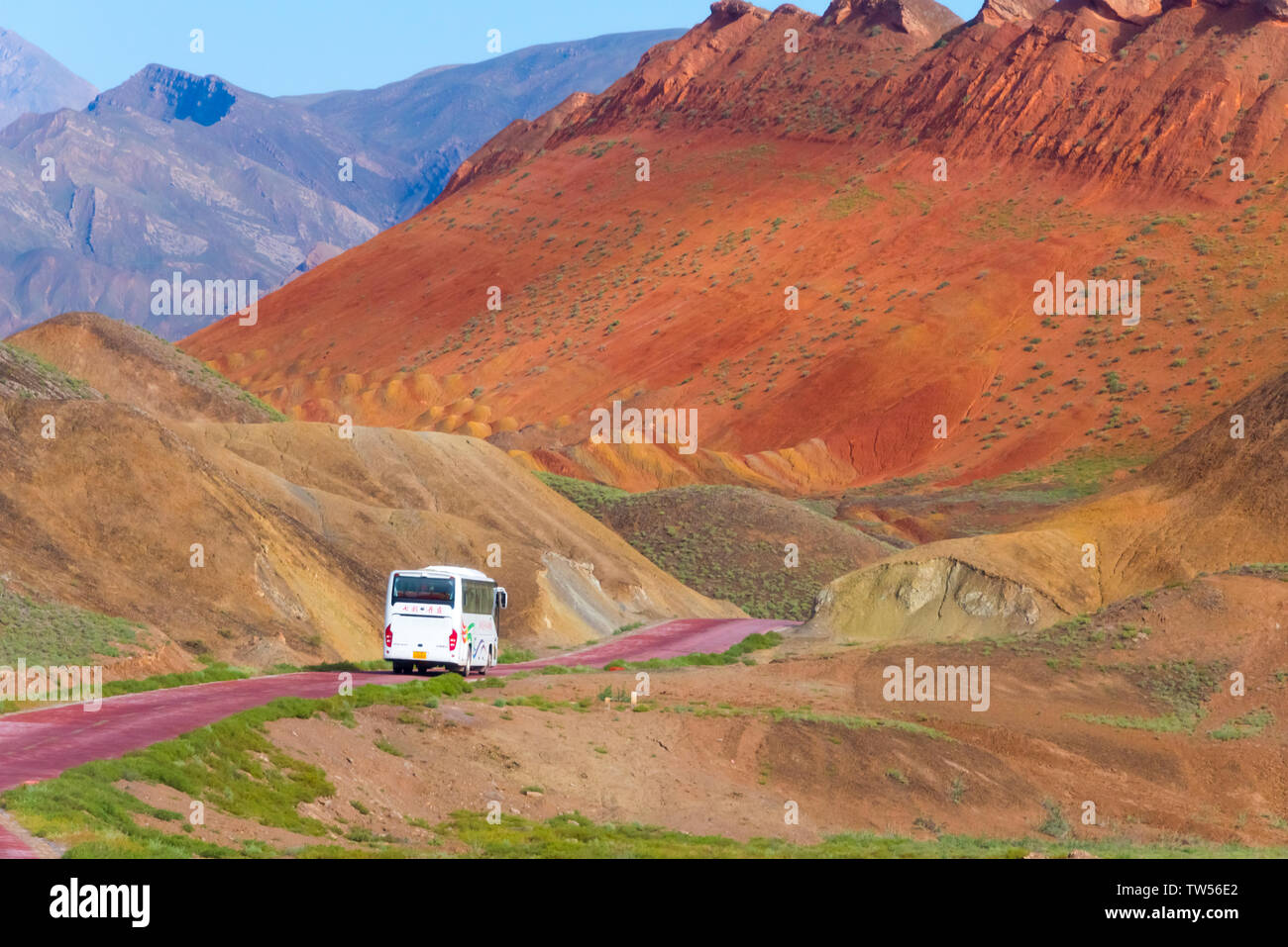 Tourist bus driving through colorful mountains in Zhangye National Geopark, Zhangye, Gansu Province, China Stock Photo