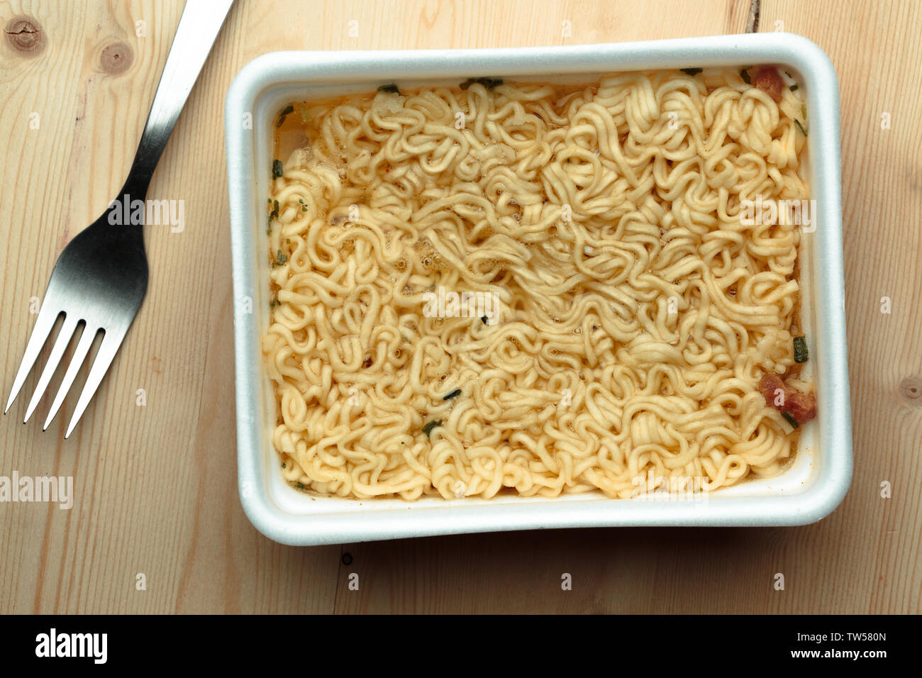 Nourishing noodles on a wooden table in a disposable plate. Stock Photo