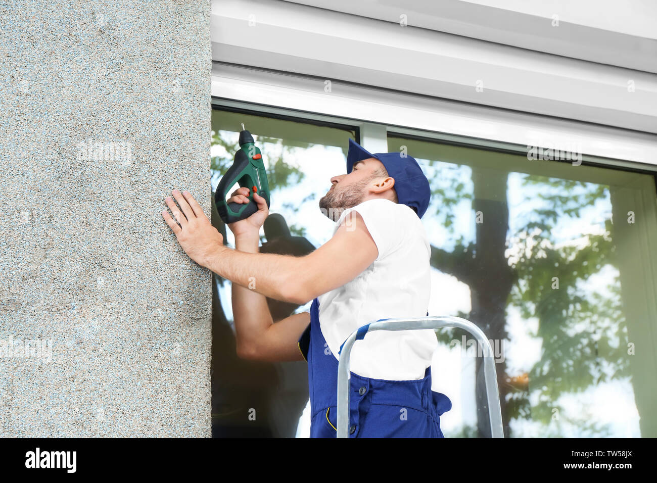Man installing roller shutter on window Stock Photo
