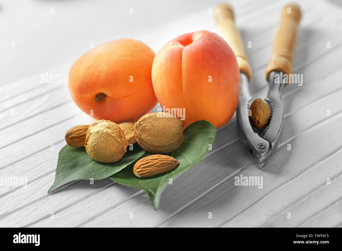 Nutcracker tool with apricots and kernels on table Stock Photo - Alamy