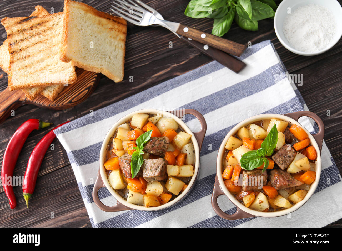Casseroles with tasty meat and potatoes on table Stock Photo