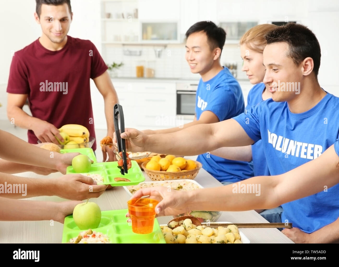 Teen volunteers serving food for homeless people indoors Stock Photo ...