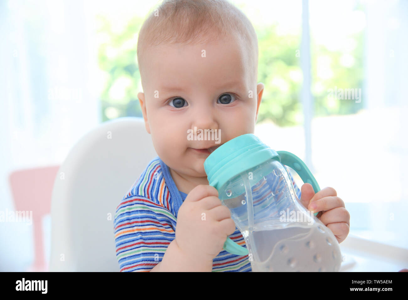 Cute baby drinking water from plastic bottle indoors Stock Photo Alamy