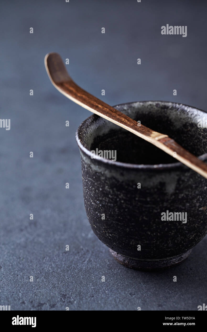Ceramic tea cup and Chashaku Matcha spoon. Symbolic image. Asian culture. Dark stone background. Close up. Copy space. Stock Photo