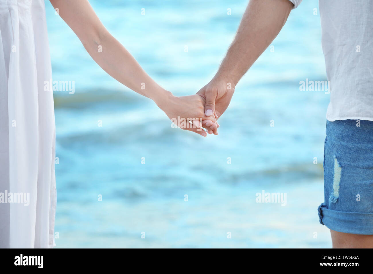 Happy young couple holding hands on sea beach Stock Photo - Alamy